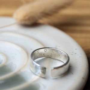 May include: A silver band ring with a heart and the inscription "S &hearts; I 3.06.2012" engraved on the inside.