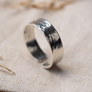 May include: A silver hammered ring with a wide band.