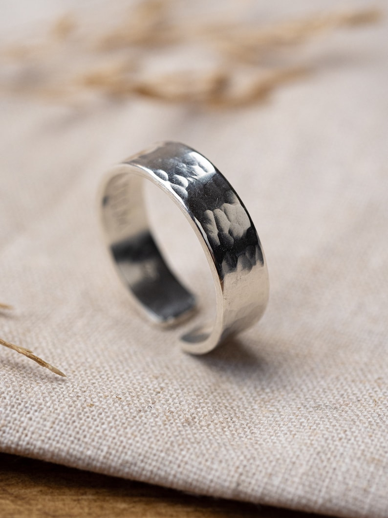 May include: A silver hammered ring with a wide band.