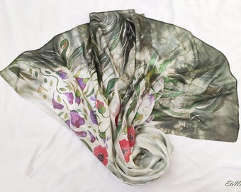 May include: A white silk scarf with a floral design. The scarf features a green, gray, and white background with pink, red, and purple flowers. The scarf is folded in a fan shape.