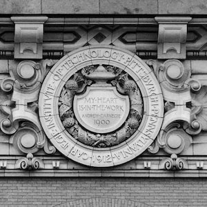 May include: Black and white photo of a stone building with a circular plaque. The plaque reads "Carnegie Institute of Technology - Pittsburgh, Pennsylvania 1912-1912". The plaque also includes the text "My heart is in the work - Andrew Carnegie 1900".