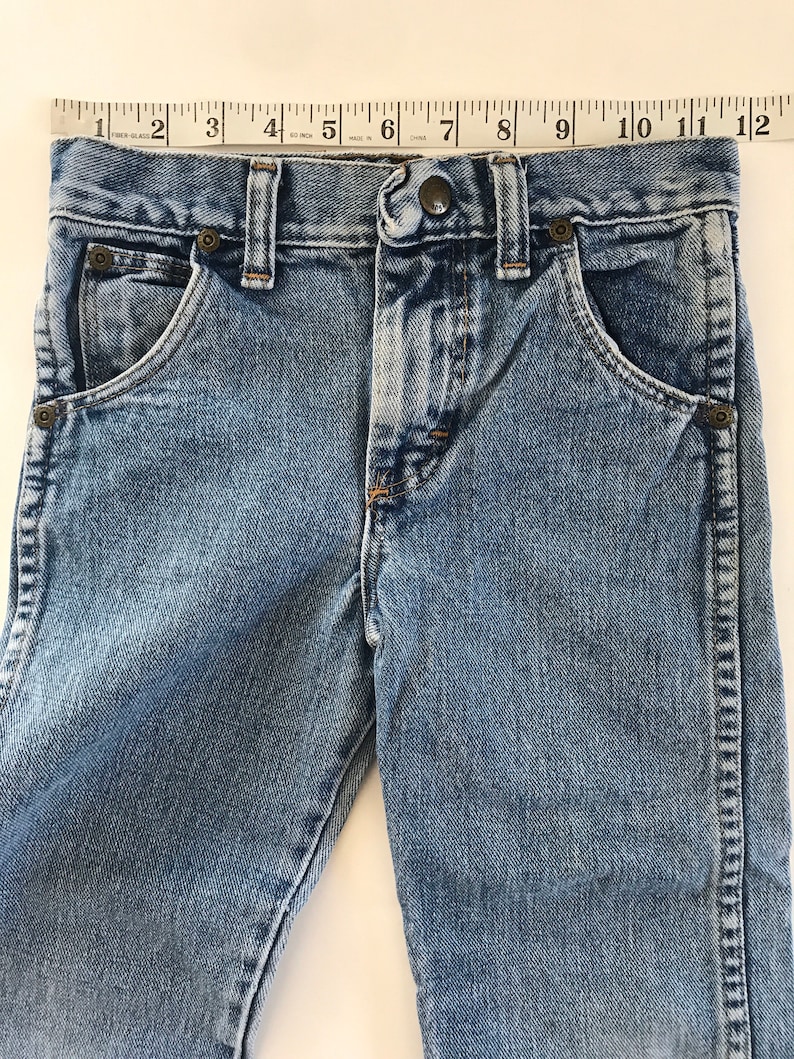 May include: A pair of light blue denim jeans with a button fly and five pockets. The jeans have a faded look and are made of a soft, comfortable fabric.