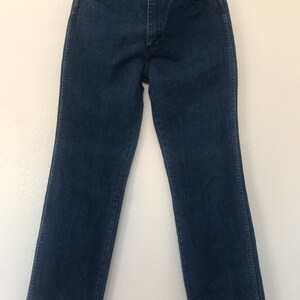 May include: A pair of dark blue denim jeans with a straight leg fit. The jeans have a classic five-pocket style and a button fly.