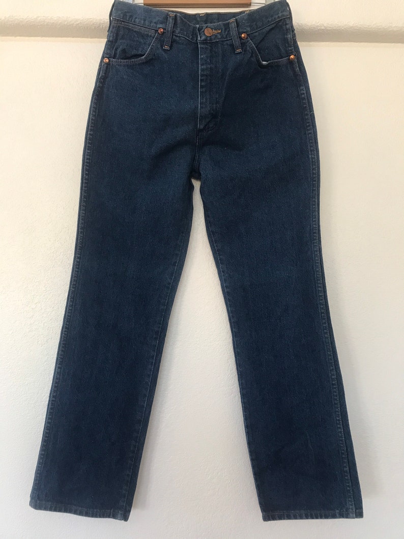 May include: A pair of dark blue denim jeans with a straight leg fit. The jeans have a classic five-pocket style and a button fly.