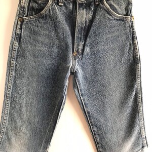 May include: A pair of blue denim shorts with a frayed hem. The shorts have a classic five-pocket design and a button fly.