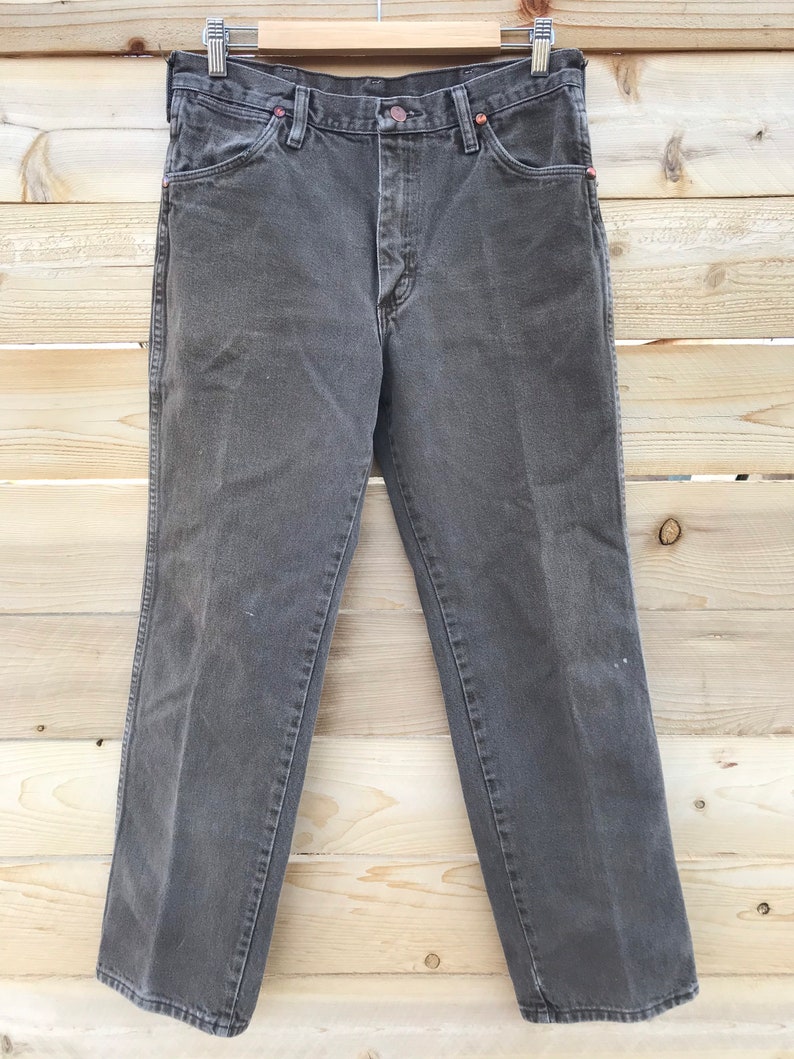 May include: A pair of dark gray denim jeans with a button fly and belt loops.