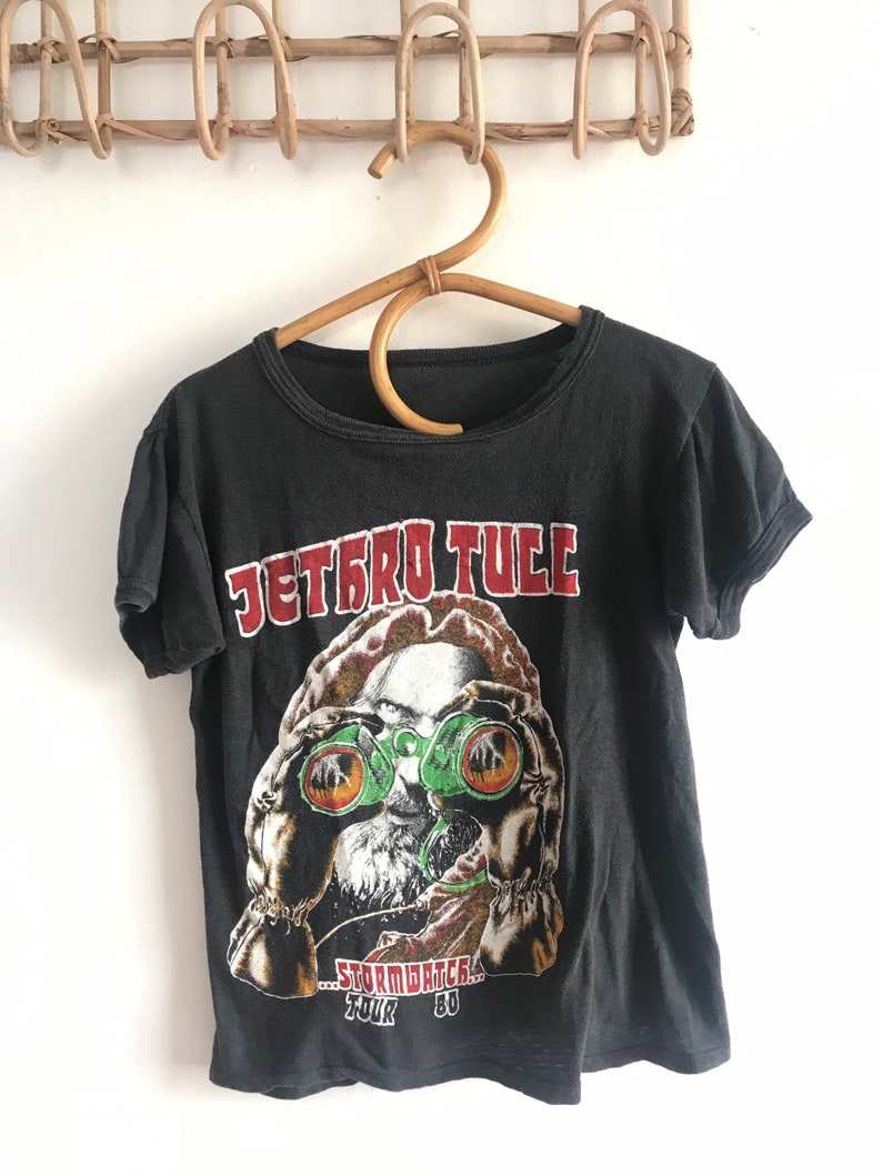 May include: Black t-shirt with a graphic of a man wearing binoculars and the text "Jethro Tull - Stormwatch Tour '80".
