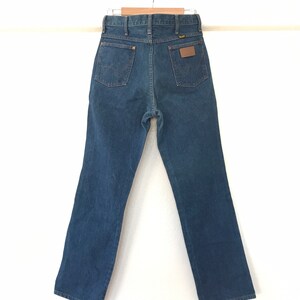 May include: A pair of dark blue denim jeans with a brown leather patch on the back pocket that says "Wrangler".