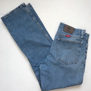 Pu&ograve; includere: Jeans in denim blu chiaro con una toppa in pelle marrone che dice "Wrangler" sulla tasca posteriore.
