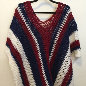 May include: A crocheted poncho with red, white, and blue stripes. The poncho has a V-neck and a loose fit.