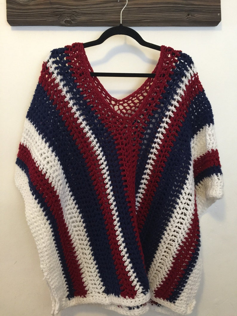 May include: A crocheted poncho with red, white, and blue stripes. The poncho has a V-neck and a loose fit.