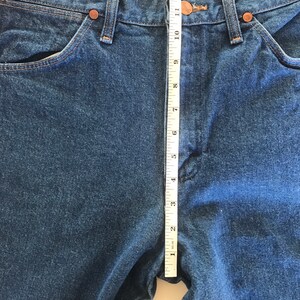 May include: A pair of blue denim jeans with a measuring tape placed along the center seam. The tape measures 12 inches.