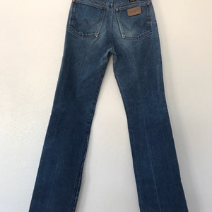 May include: A pair of blue denim jeans with a brown leather patch on the back pocket that says "Wrangler".
