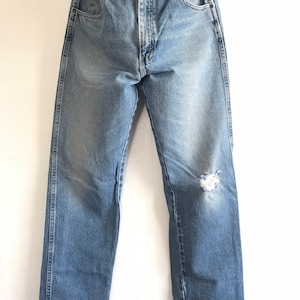 Pu&ograve; includere: Jeans in denim blu chiaro con un ginocchio consumato e una gamba dritta.
