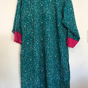 Puede incluir: T&uacute;nica azul turquesa con estampado de leopardo blanco y turquesa. La t&uacute;nica tiene ribetes rosas en las mangas y una peque&ntilde;a abertura en la parte inferior.