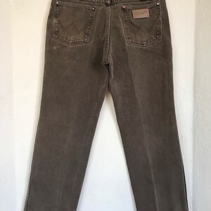 May include: A pair of brown denim jeans with a leather patch on the back pocket that says "Wrangler".