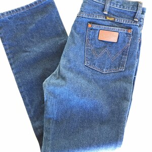 May include: A pair of blue denim jeans with a brown leather patch on the back pocket that says "Wrangler".