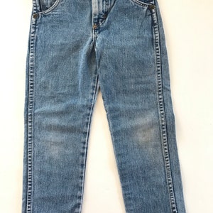May include: A pair of light blue denim jeans with a button fly and five pockets.