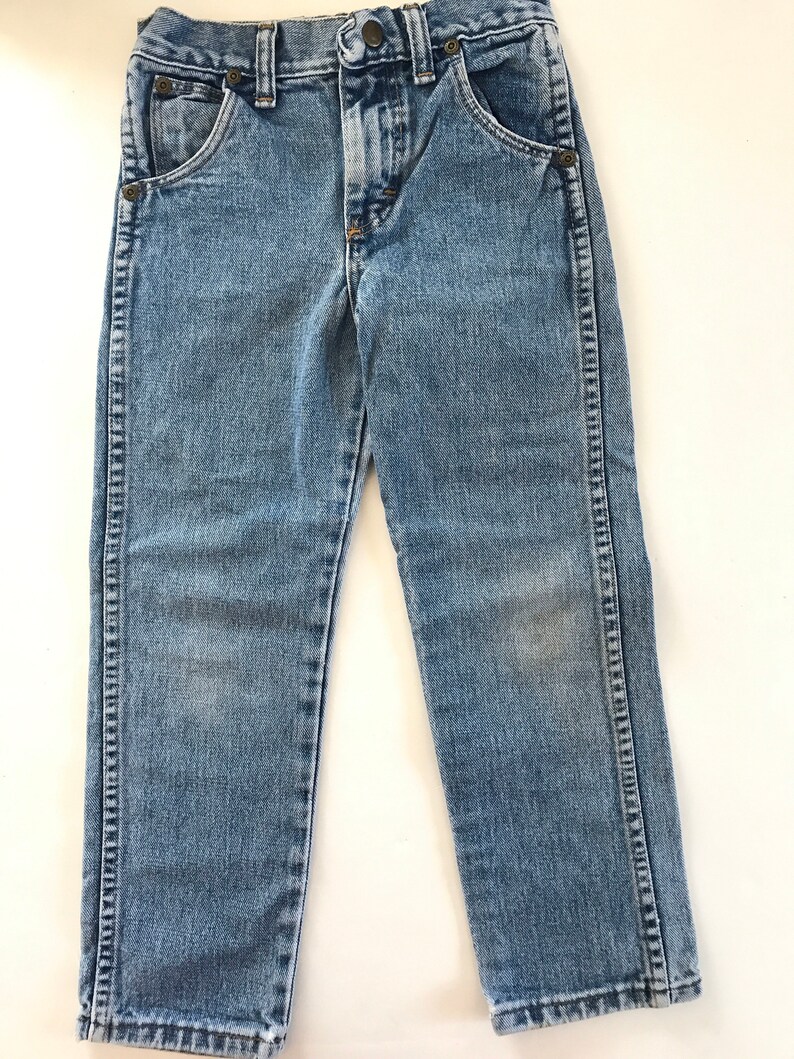 May include: A pair of light blue denim jeans with a button fly and five pockets.