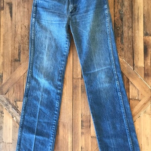 May include: A pair of blue denim jeans with a straight leg fit. The jeans have a button fly and belt loops.