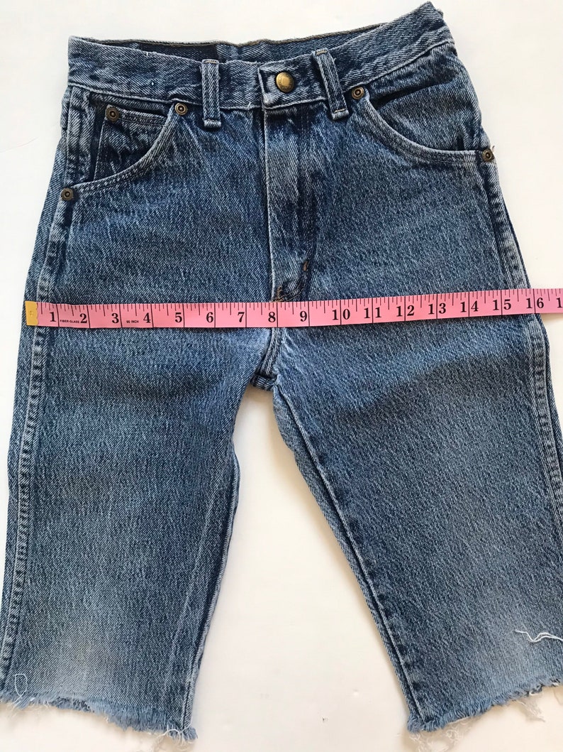 May include: A pair of blue denim shorts with a frayed hem. The shorts have a light wash and are made of a soft, comfortable fabric. The shorts measure 16 inches in length.