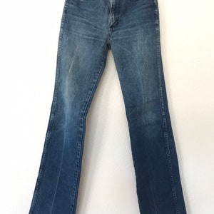 May include: A pair of blue denim jeans with a bootcut leg. The jeans have a classic five-pocket style and a button fly.