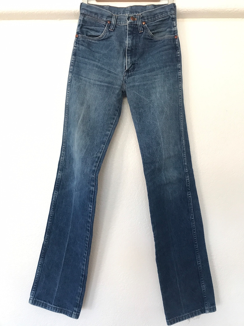 May include: A pair of blue denim jeans with a bootcut leg. The jeans have a classic five-pocket style and a button fly.