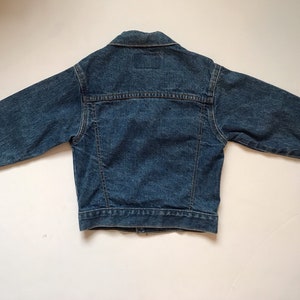 K&ouml;nnte beinhalten: Eine blaue Jeansjacke mit langen &Auml;rmeln und Knopfleiste.