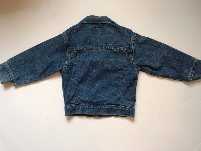 K&ouml;nnte beinhalten: Eine blaue Jeansjacke mit langen &Auml;rmeln und Knopfleiste.