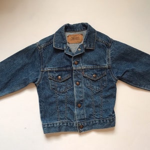 K&ouml;nnte beinhalten: Eine blaue Jeansjacke mit Knopfleiste, zwei Brusttaschen und einem Levi's-Etikett auf der linken Seite.