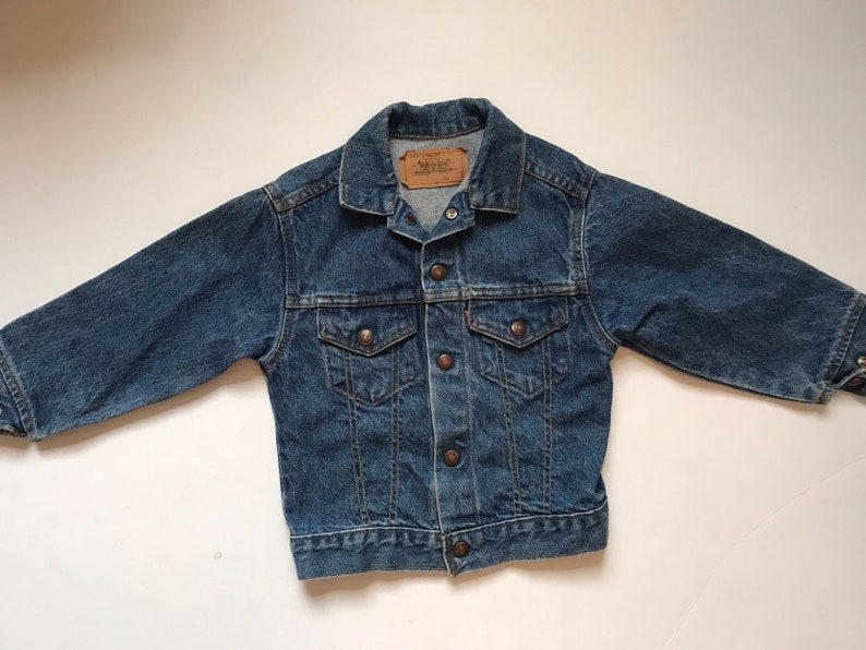 K&ouml;nnte beinhalten: Eine blaue Jeansjacke mit Knopfleiste, zwei Brusttaschen und einem Levi's-Etikett auf der linken Seite.