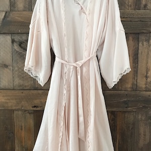 May include: A long, white satin robe with lace trim and a matching sash. The robe has a V-neckline and long sleeves.
