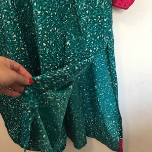 Puede incluir: Una t&uacute;nica azul turquesa con estampado de leopardo blanco y ribete rosa. La t&uacute;nica tiene una abertura lateral y est&aacute; hecha de una tela ligera.