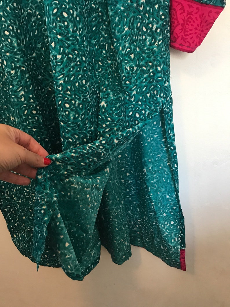 Puede incluir: Una t&uacute;nica azul turquesa con estampado de leopardo blanco y ribete rosa. La t&uacute;nica tiene una abertura lateral y est&aacute; hecha de una tela ligera.