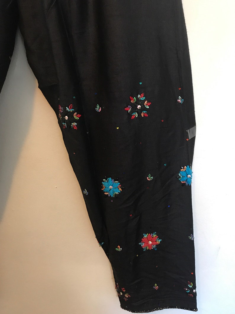 May include: Black pants with colorful embroidered flowers and sequins.