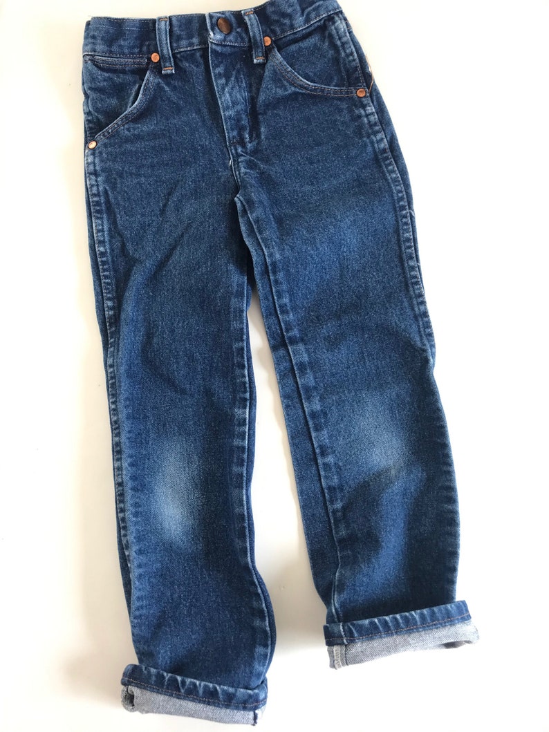 May include: Blue denim jeans with copper rivets and pockets. The jeans have a classic five-pocket design and are cuffed at the ankles. The jeans are made of a durable denim fabric and are suitable for everyday wear.
