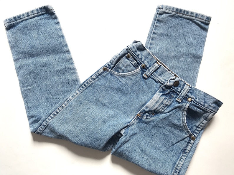 May include: A pair of light blue denim jeans with a button fly and five pockets.