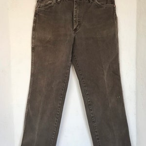 May include: A pair of dark brown denim jeans with a straight leg fit. The jeans have a button fly and belt loops.