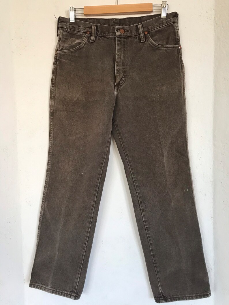 May include: A pair of dark brown denim jeans with a straight leg fit. The jeans have a button fly and belt loops.