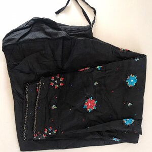 May include: Black cotton pants with a drawstring waist and embroidered floral designs in red, blue, and green.