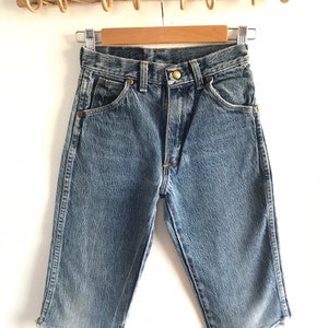 May include: A pair of light blue denim shorts with a frayed hem. The shorts have a classic five-pocket design and a button fly.