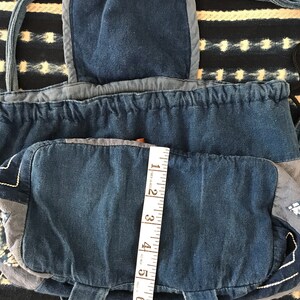 Puede incluir: Una bolsa de cord&oacute;n de mezclilla azul con un bolsillo de solapa y una cinta m&eacute;trica. La bolsa est&aacute; hecha de mezclilla de retazos y tiene un cierre de cord&oacute;n.