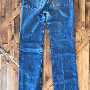 May include: A pair of blue denim jeans with a brown leather patch on the back pocket that says "Wrangler".
