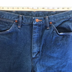 May include: A pair of blue denim jeans with a copper button and rivets. The jeans have two front pockets and two back pockets.