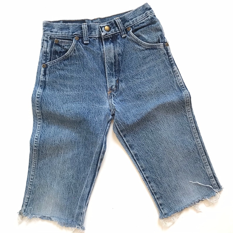 May include: A pair of light blue denim shorts with a frayed hem. The shorts have a classic five-pocket design and a button fly.