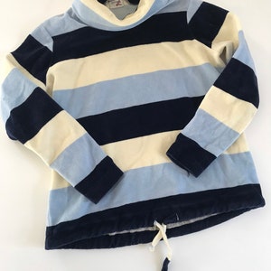 May include: A striped long-sleeved turtleneck sweater with blue, white, and light blue stripes. The sweater has a drawstring at the bottom.