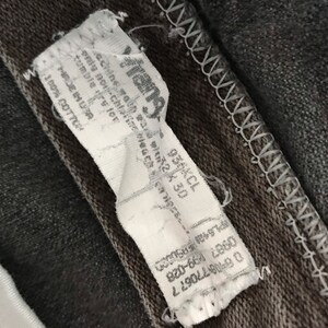 May include: A white tag with black text attached to a dark gray fabric. The tag reads "Frang", "Machine wash cold", "Tumble dry low", "Made in USA", "100% Cotton", "PL642 EPSUCCO", "0987 1899-028", "08770677", and "936KCL 230".