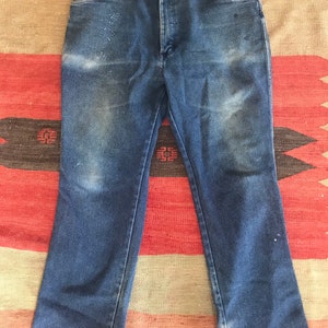 May include: A pair of blue denim jeans with a straight leg fit. The jeans have a classic five-pocket style and a button fly.