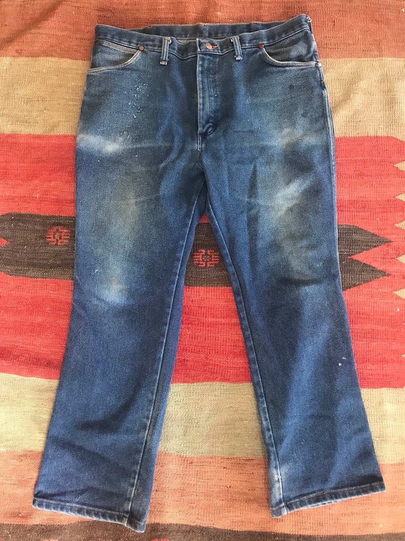 May include: A pair of blue denim jeans with a straight leg fit. The jeans have a classic five-pocket style and a button fly.