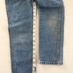 May include: A pair of light blue denim jeans with a seam down the outside of each leg. The jeans are measured with a tape measure, showing a length of 19 inches.